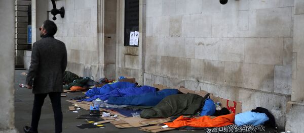 A man walks past homeless people sleeping rough in London A man walks past homeless people sleeping rough in London - Sputnik International
