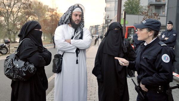 A police woman carries out an identity check of a wife  wearing a full-face veil of French owner of a chain of butcher’s and grocery shops, Lies Hebbadj (C), outside the court of justice where she was to appear because she violated France's niqab ban, on November 21, 2011 in the French western city of Nantes - Sputnik International
