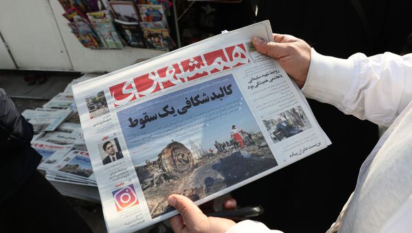 An Iranian holds a newspaper with a picture of the debris of the Ukrainian plane that crashed in Tehran earlier this week, outside a news stand in the Islamic republic's capital on January 11, 2020. - Sputnik International