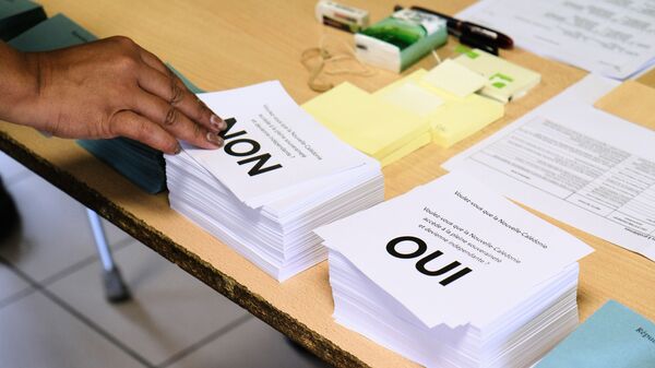 A person picks up a voting form as he prepares to cast his vote at a polling station in the referendum on independence on the French South Pacific territory of New Caledonia in Noumea on October 4, 2020 - Sputnik International