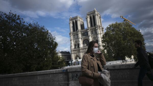 A woman walks by Notre Dame cathedral Saturday Sept.26, 2020 in Paris. While France suffered testing shortages early in the pandemic, ramped-up testing since this summer has helped authorities track a rising tide of infections across the country. - Sputnik International