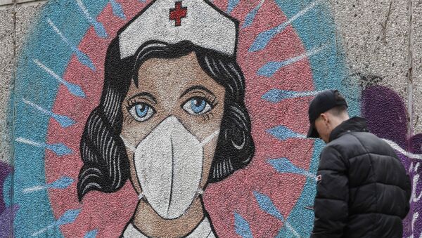 A man passes a graffiti by street artist 'Uzey', depicting a nurse as a superhero amid the coronavirus pandemic on a wall in Hamm, Germany, 28 September 2020. - Sputnik International