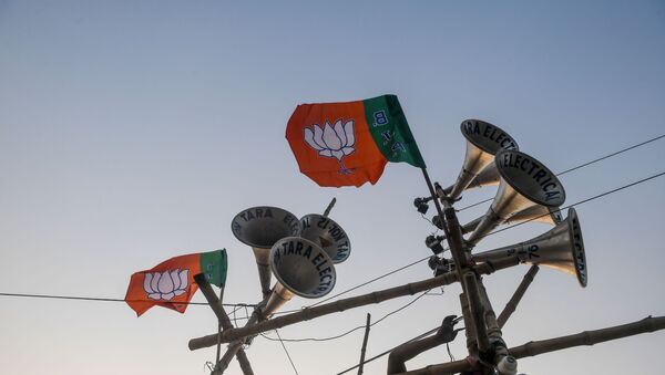 A worker ties a Bharatiya Janata Party (BJP) flag on a structure bearing loudspeakers to prepare for the next day the political rally of Home Minister Amit Shah, in Kolkata on February 29, 2020. - Sputnik International