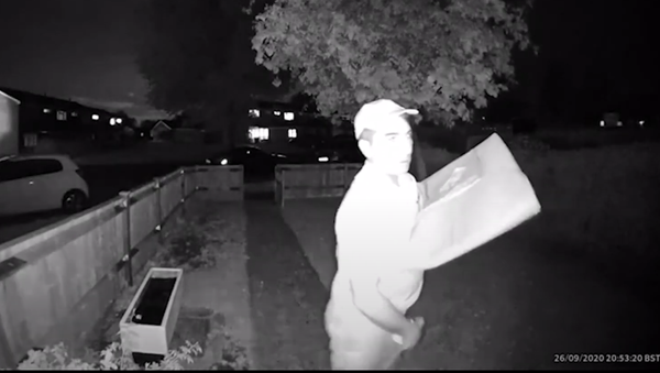 A screenshot from surveillance camera footage of a Domino’s Pizza delivery driver rubbing an ice cream container on his crotch while waiting for a customer to open the door. - Sputnik International