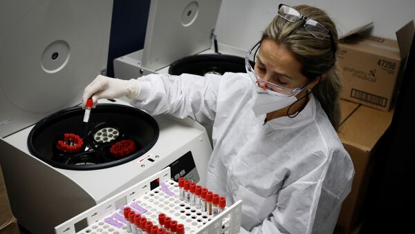 A health worker takes test tubes with plasma and blood samples from a centrifuge after a separation process during a coronavirus disease (COVID-19) vaccination study at the Research Centers of America, in Hollywood, Florida, U.S., September 24, 2020. REUTERS/Marco Bello - Sputnik International