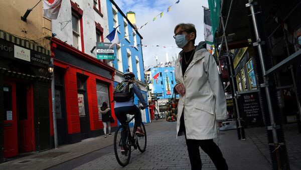 A woman wearing a protective face mask walks along a street as the National Public Health Emergency Team (NPHET) announced recommendations that the government implement the highest level of COVID-19 restrictions to Level 5, amid the coronavirus disease (COVID-19) pandemic, in the City centre of Galway, Ireland, October 5, 2020 - Sputnik International