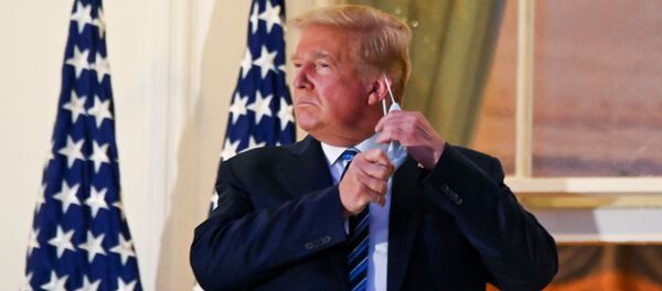 U.S. President Donald Trump pulls off his protective face mask as he poses atop the Truman Balcony of the White House after returning from being hospitalized at Walter Reed Medical Center for coronavirus disease (COVID-19) treatment, in Washington, U.S. October 5, 2020. REUTERS/Erin Scott  - Sputnik International