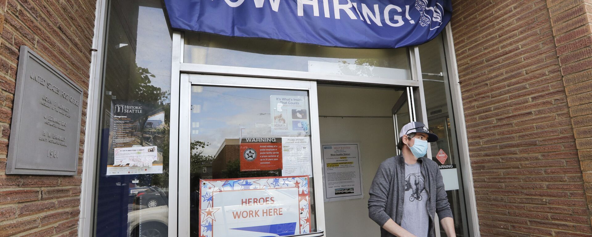 In this Thursday, June 4, 2020 file photo, a customer walks out of a U.S. Post Office branch and under a banner advertising a job opening, in Seattle. The job market took a big step toward healing in May 2020, though plenty of damage remains, as a record level of hiring followed record layoffs in March and April. The Labor Department reported Tuesday, July 7, 2020 that the number of available jobs rose sharply as well, but remained far below pre-pandemic levels.  - Sputnik International, 1920, 18.02.2021