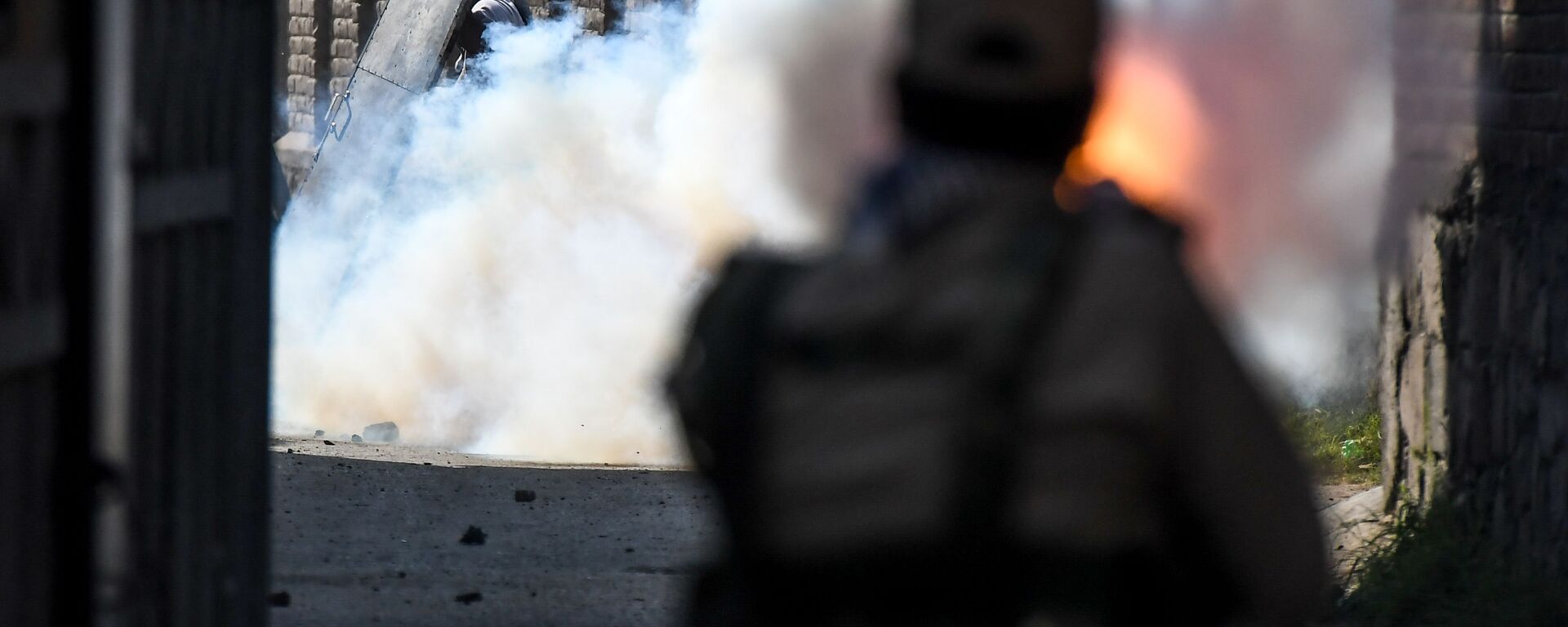 A security personnel (R) fires tear gas towards protesters during clashes with government forces in Batamaloo area of Srinagar on September 17, 2020.  - Sputnik International, 1920, 19.01.2022