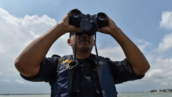 A member of the Malaysian Maritime Enforcement Agency officer uses a pair of binoculars to scan the sea during the rescue operation for the missing sailors from the USS John S. McCain off the Johor coast of Malaysia on August 24, 2017. - The US destroyer John S. McCain collided with a tanker early on August 21 as the warship prepared to make a routine port call in Singapore, leaving a gaping hole in its hull and 10 sailors missing. - Sputnik International