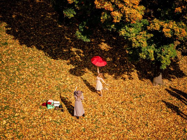 A woman hold an umbrella and poses for a photo on a sunny autumn day in Tsaritsyno Park in Moscow on 2 October 2020. - Sputnik International