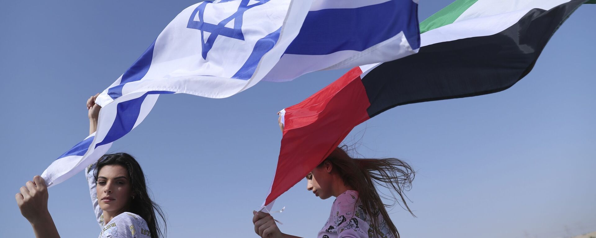 Israeli model May Tager, left, holds Israel's blue-and-white flag bearing the Star of David while next to her Anastasia Bandarenka, a Dubai-based model originally from Russia, waves the Emirati flag, during a photo shoot in Dubai, United Arab Emirates, 8 September 2020 - Sputnik International, 1920, 26.02.2021