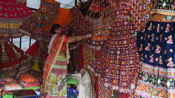 A vendor wearing a facemask as a protection against the Covid-19 Coronavirus, arranges traditional dresses ahead of the forthcoming Hindu festival 'Navratri', a nine-night dance festival, at Law Garden Bazaar in Ahmedabad on September 21, 2020. - Sputnik International