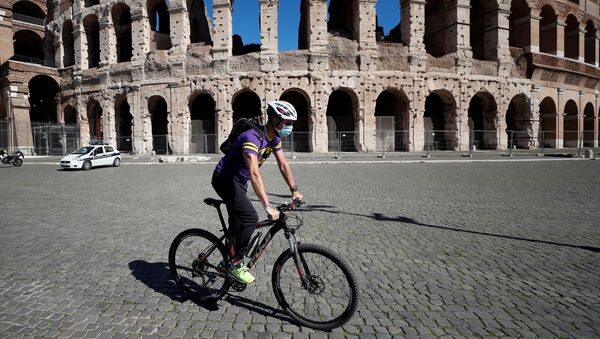 A man wearing a protective face mask cycles past the Colosseum as local authorities in the Italian capital Rome ordered face coverings to be worn at all times outdoors, in an effort to counter the spread of the coronavirus disease (COVID-19), in Rome, Italy, October 8, 2020. - Sputnik International