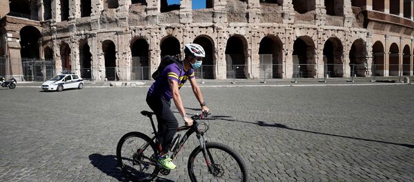 A man wearing a protective face mask cycles past the Colosseum as local authorities in the Italian capital Rome ordered face coverings to be worn at all times outdoors, in an effort to counter the spread of the coronavirus disease (COVID-19), in Rome, Italy, October 8, 2020. - Sputnik International