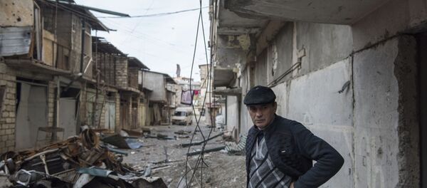 A man stands near a house with a row of destroyed barns in the background in Stepanakert, a self-proclaimed Republic of the Nagorno-Karabakh.  - Sputnik International