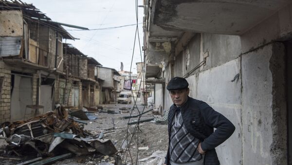 A man stands near a house with a row of destroyed barns in the background in Stepanakert, a self-proclaimed Republic of the Nagorno-Karabakh.  - Sputnik International