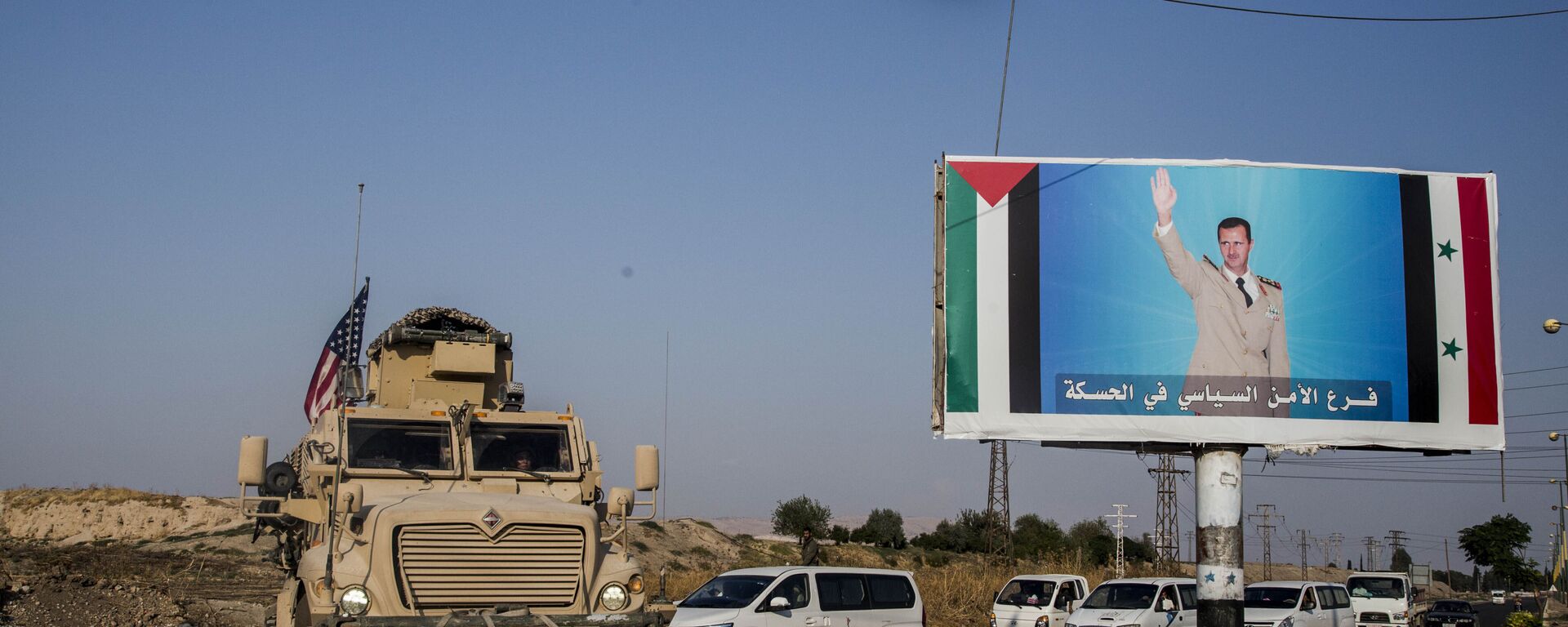 FILE - In this Saturday, 26 October 2019 file photo, a US military vehicle drives south of the northeastern city of Qamishli, likely heading to the oil-rich Deir el-Zour area where there are oil fields, or possibly to another base nearby, as it passes by a poster showing Syrian President Bashar Assad. - Sputnik International, 1920, 13.10.2020