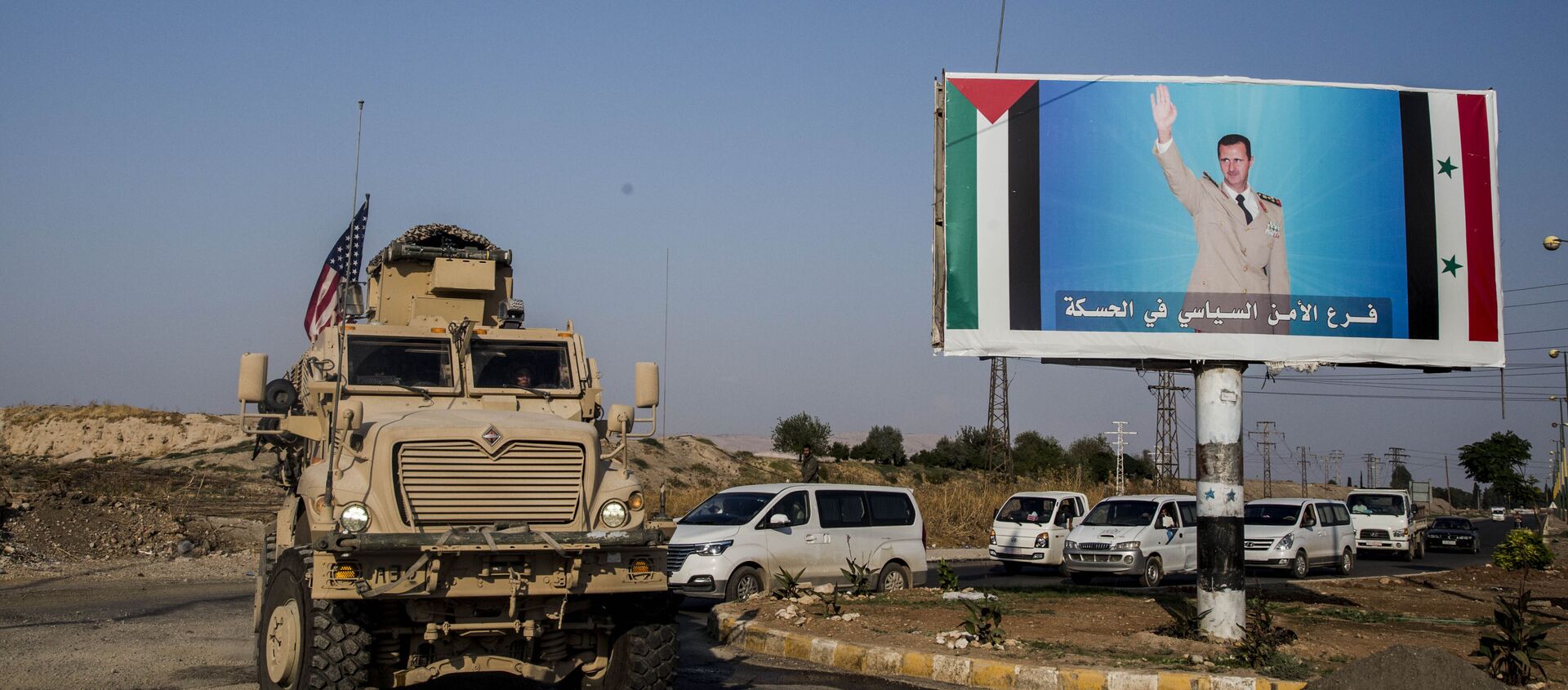 FILE - In this Saturday, 26 October 2019 file photo, a US military vehicle drives south of the northeastern city of Qamishli, likely heading to the oil-rich Deir el-Zour area where there are oil fields, or possibly to another base nearby, as it passes by a poster showing Syrian President Bashar Assad. - Sputnik International, 1920, 13.10.2020