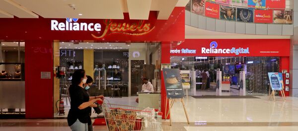 A customer wearing a protective mask pushes a trolley with grocery items past Reliance Jewels and Reliance Digital stores in Mumbai, India. - Sputnik International