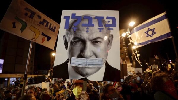 Israeli protesters hold signs during a demonstration against Israeli Prime Minister Benjamin Netanyahu outside the Prime Minister's residence in Jerusalem, Saturday, Sept. 12, 2020. - Sputnik International