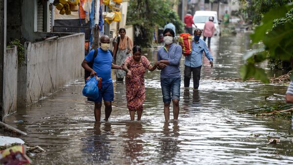 Residents carrying their belongings help a woman (C) while making their way down a flooded street following heavy rains in Hyderabad on 14 October 2020.  - Sputnik International
