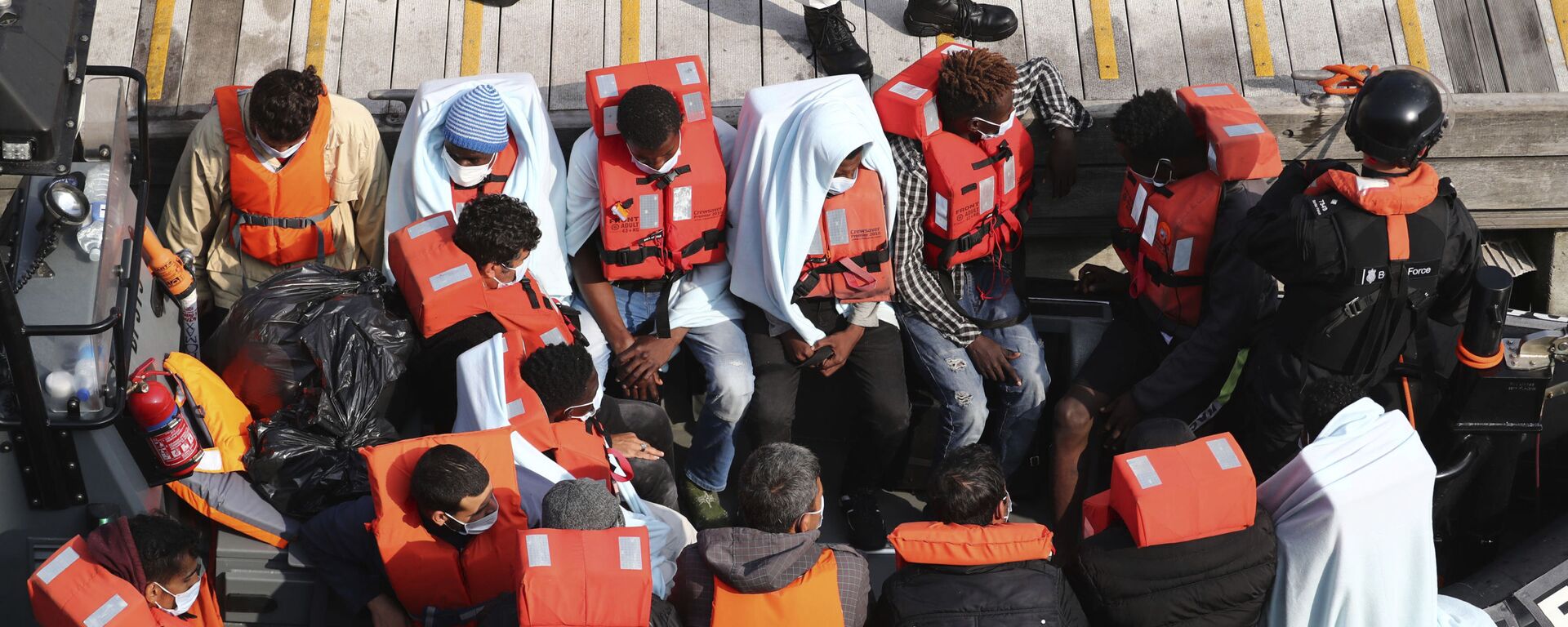 A group of people, thought to be migrants wait on a Border Force rib to come ashore at Dover marina in Kent, England after a small boat incident in the English Channel, Tuesday Sept. 22, 2020.  - Sputnik International, 1920, 15.04.2022