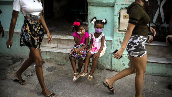 Девочки в масках ждут своих родителей, сидя на стуле в Гаване, Куба - Sputnik International