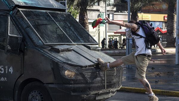 A demonstrator clashes with a riot police van during a protest against Chilean President Sebastian Pinera's government in Santiago on 16 October 2020.  - Sputnik International