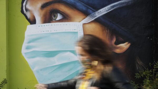 A woman walks in from of a mural painting of a nurse, in Milan, Italy, Wednesday, Oct. 14, 2020. Coronavirus infections are surging again in the Italian northern region where the pandemic first took hold in Europe, putting pressure again on hospitals and health care workers. - Sputnik International