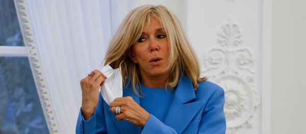 In this file photo taken on September 28, 2020, French President's wife Brigitte Macron takes off her face mask after a welcoming ceremony at the Presidential Palace in Vilnius, Lithuania. - Brigitte Macron has gone into a 7-day self-isolation period after being in contact with a person who has been tested positive with Covid-19, her entourage told AFP on October 19, 2020. Brigitte Macron, who does not show any symptoms of the disease, was in contact on October 15 with a person declared positive for Covid-19 on October 19, and showing symptoms, according to her entourage.  - Sputnik International