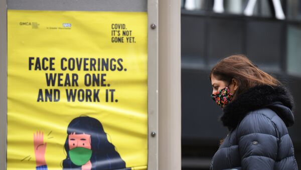 A woman wearing a facemask walks past a poster urging people to wear face coverings, in Manchester, north west England on October 13, 2020, as the number of cases of the novel coronavirus COVID-19 continue to rise. - Sputnik International