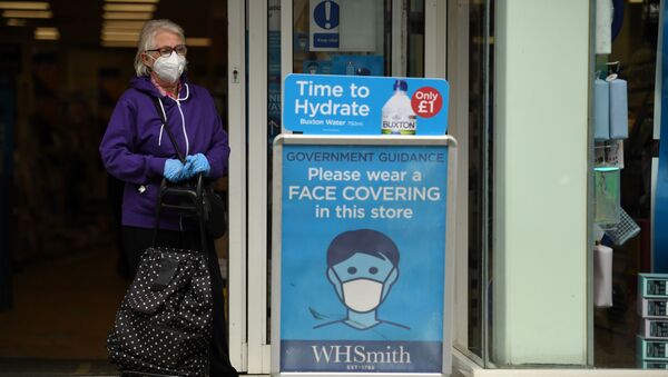 A shopper wearing a face mask stands alongside a sign calling for the wearing of face coverings in shops, in the city centre of Sheffield, south Yorkshire on July 24, 2020, as lockdown restrictions continue to be eased during the novel coronavirus COVID-19 pandemic - Sputnik International