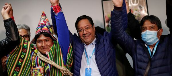 Presidential candidate Luis Arce of the Movement to Socialism party (MAS) reacts next to vice presidential candidate David Choquehuanca, who wears a protective face mask, after addressing the media during the presidential election in La Paz, Bolivia, October 19, 2020 - Sputnik International