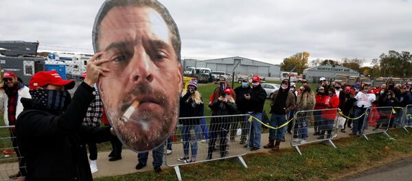 A supporter of U.S. President Donald Trump holds up a photo of Hunter Biden for fellow supporters as they wait in line to attend Trump's campaign event at Erie International Airport in Erie, Pennsylvania, U.S. October 20, 2020. - Sputnik International