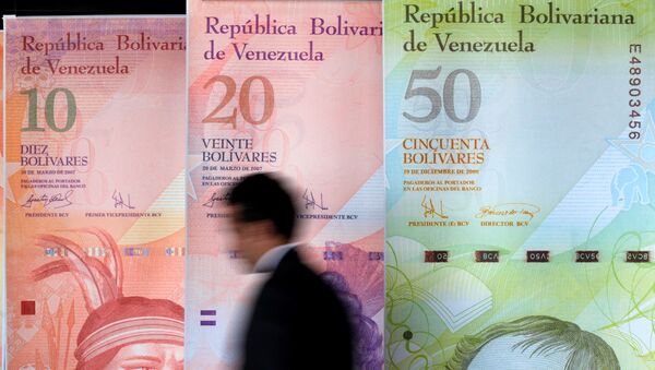 A man walks past big samples of Venezuelan banknotes at the Central Bank headquarters in Caracas August 22, 2013. - Sputnik International