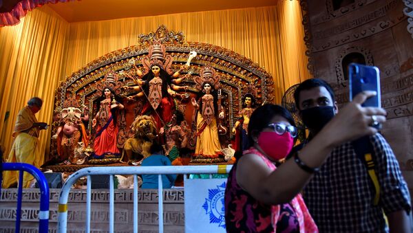 Hindu devotees take a selfie in front of an idol of Hindu goddess Durga before prayer at a cordoned off pandal or temporary platform, on the first day of Durga Puja festival, amidst the spread of COVID-19 in Kolkata, India, October 22, 2020 - Sputnik International