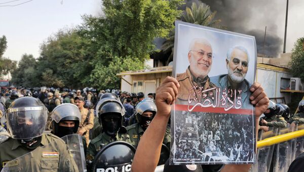 A supporter of Hashid Shaabi (Popular Mobilization Forces) holds a picture of late Iran's Quds Force top commander Qassem Soleimani and Iraqi militia commander Abu Mahdi al-Muhandis who were killed in a U.S. airstrike during a protest in Baghdad, Iraq October 17, 2020 - Sputnik International