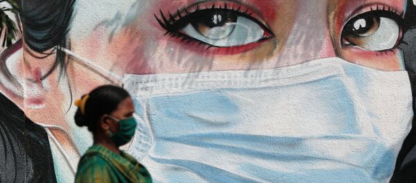 A woman walks past a graffiti of a girl wearing a protective mask amidst the spread of the coronavirus disease (COVID-19) in Mumbai, India, October 23, 2020 - Sputnik International