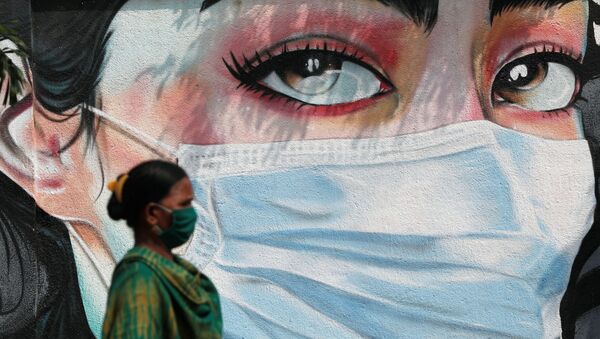 A woman walks past a graffiti of a girl wearing a protective mask amidst the spread of the coronavirus disease (COVID-19) in Mumbai, India, October 23, 2020 - Sputnik International
