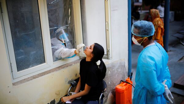 A health worker in personal protective equipment (PPE) collects a sample using a swab from a person at a local health centre to conduct tests for the coronavirus disease (COVID-19), amid the spread of the disease, in New Delhi, India October 7, 2020 - Sputnik International