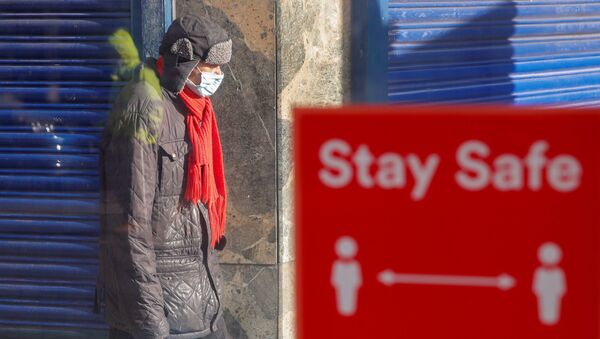  A person wearing a protective mask walks near a social distancing sign, amid the outbreak of the coronavirus disease (COVID-19), in Coventry, Britain, 25 October 2020. - Sputnik International