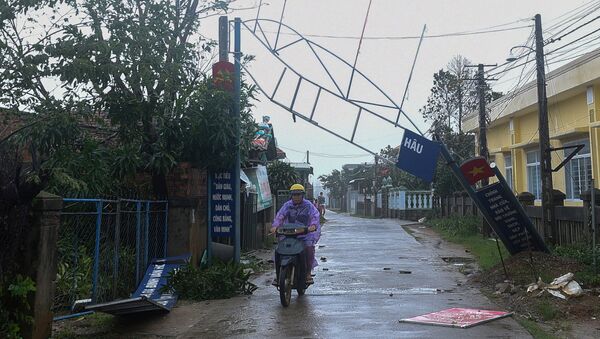 A man bikes past a broken sign as the Typhoon Molave lashes Vietnam's coast in Binh Chau village, Quang Ngai province October 28, 2020 - Sputnik International