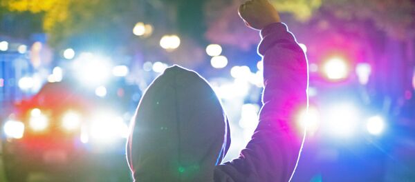 A woman holds up her fist as police declare an unlawful assembly after a vigil and march marking the shooting death by police of Black man Kevin E. Peterson Jr. in Vancouver, Washington - Sputnik International