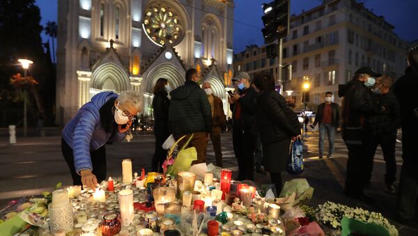 A woman lights a candle outside Notre-Dame de l'Assomption Basilica in Nice on October 31, 2020, to pay tribute to the victims two days after a knife attacker killed three people, cutting the throat of two, inside the church of the French Riviera city, and police arrest a young Tunisian migrant from Sfax who arrived in Europe only last month, according to French prosecutors. (Photo by Valery HACHE / AFP) - Sputnik International