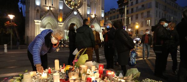A woman lights a candle outside Notre-Dame de l'Assomption Basilica in Nice on October 31, 2020, to pay tribute to the victims two days after a knife attacker killed three people, cutting the throat of two, inside the church of the French Riviera city, and police arrest a young Tunisian migrant from Sfax who arrived in Europe only last month, according to French prosecutors. (Photo by Valery HACHE / AFP) - Sputnik International