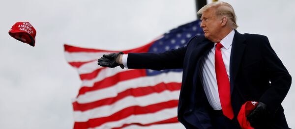 U.S. President Donald Trump tosses out Make America Great Again (MAGA) caps as he arrives for a campaign rally at Oakland County International Airport in Waterford Township, Michigan, U.S., October 30, 2020. REUTERS/Carlos Barria - Sputnik International
