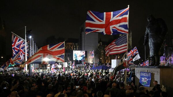 A Brexit supporter waves a US and Union flags as they wait for the festivities to begin in Parliament Square, the venue for the Leave Means Leave Brexit Celebration in central London on January 31, 2020, the day that the UK formally leaves the European Union - Sputnik International