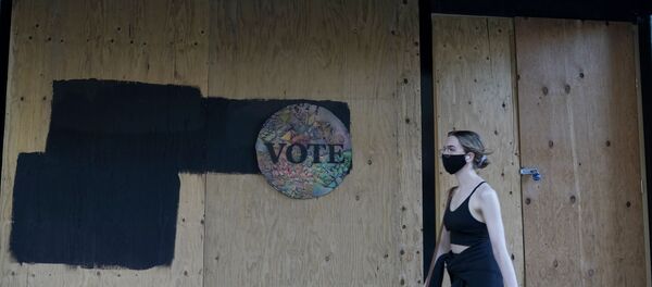 A woman walks past a Vote sign on wooden boards covering the exterior of Chloe Gallery in San Francisco, Monday, Nov. 2, 2020, ahead of Election Day.  - Sputnik International