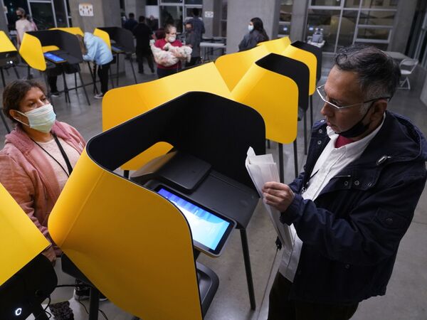 Fernando Dejo, right, and Sabina Vasquez retrieve paper votes from ballot-marking devices, or vote recorders, as a polling station closes in Los Angeles on Tuesday, 3 November 2020.  - Sputnik International